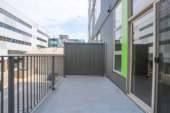 A black metal fence separates a parking lot from a building.